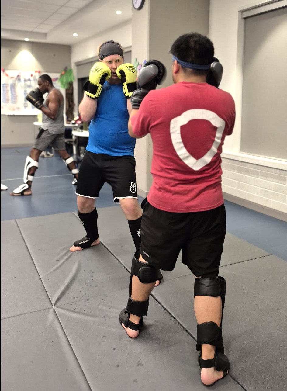 Two kickboxers sparring with gloves and shin guards in a gym session
