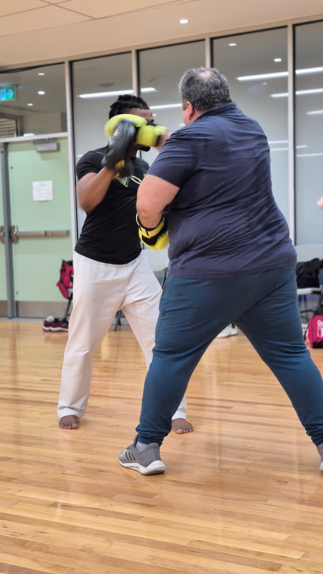 An adult student throws a cross while the instructor covers up behind pads