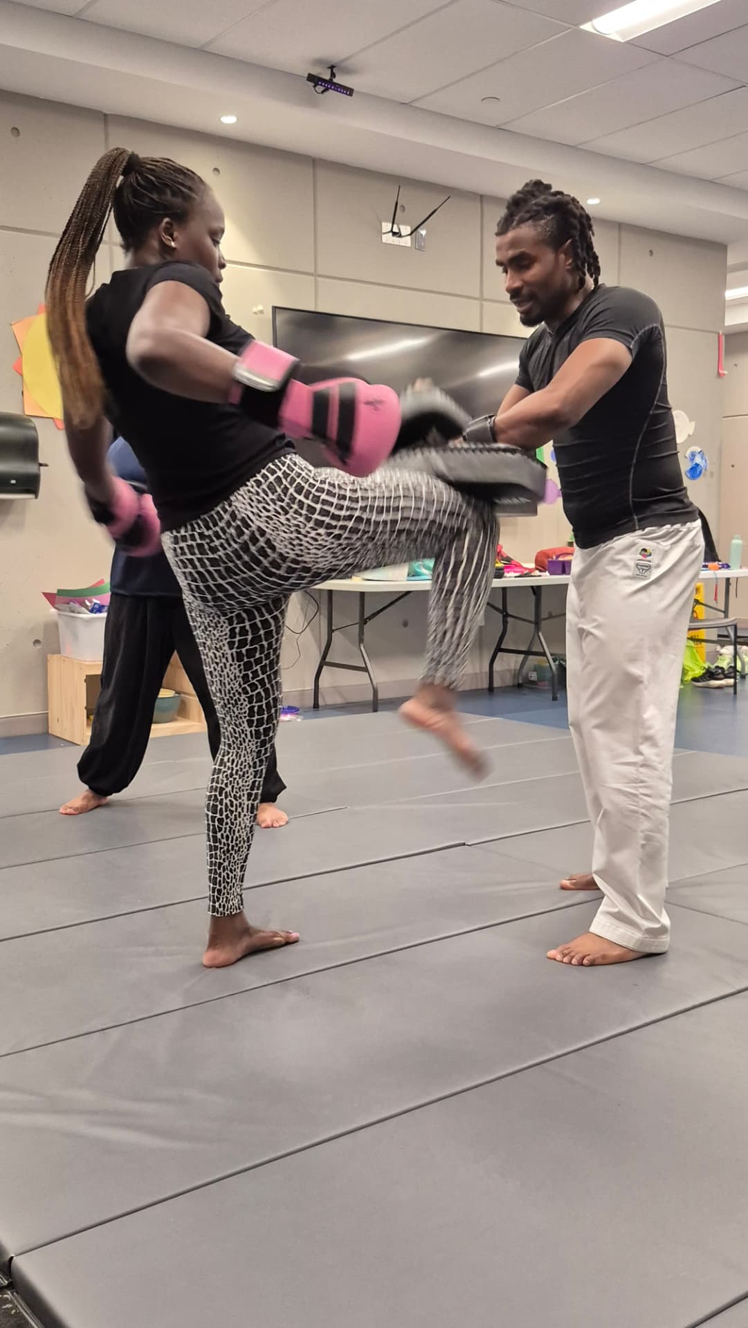 An instructor resets the pads as an adult student prepares the next strike
