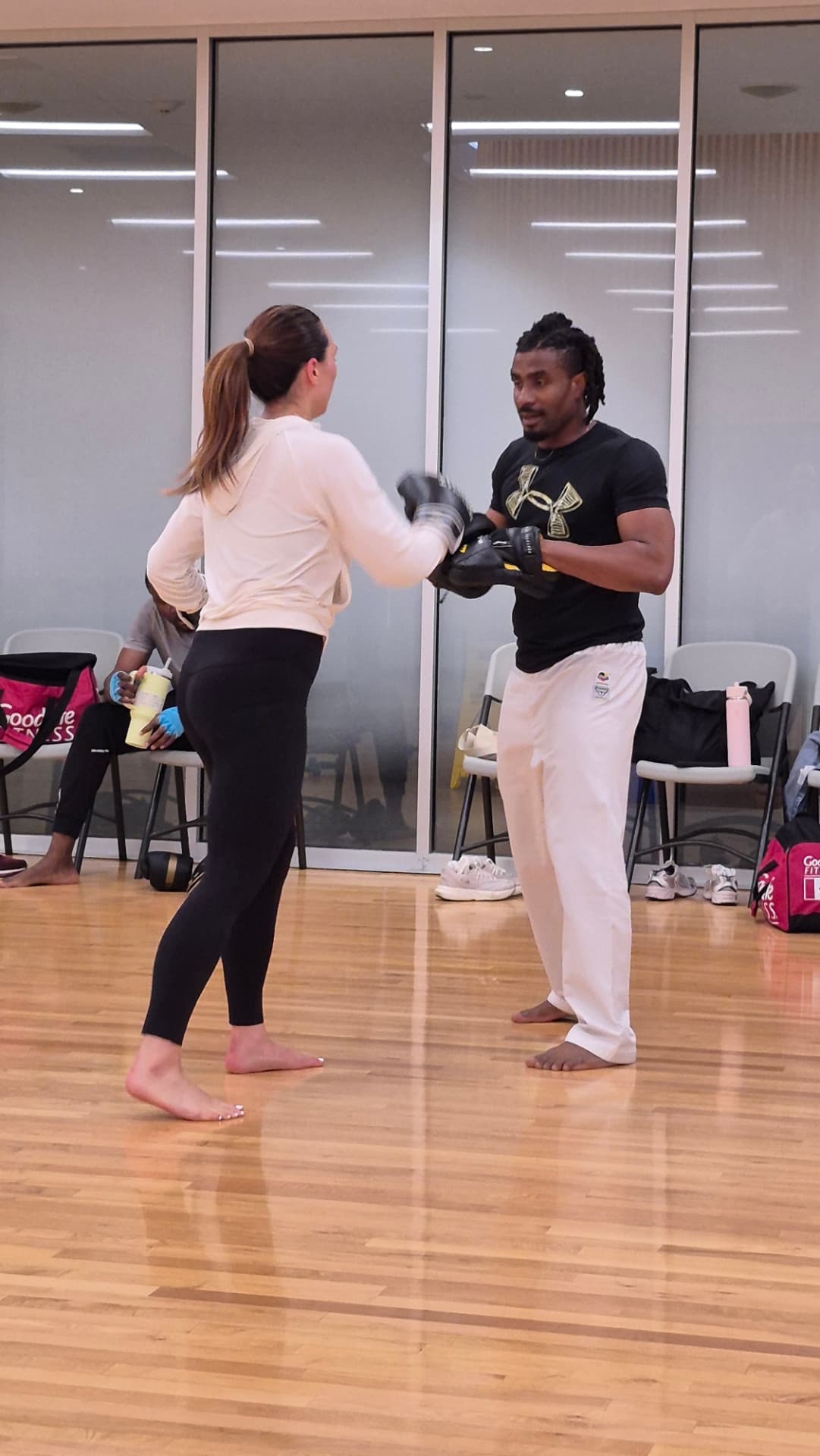 An adult student punches into the instructor's focus mitt