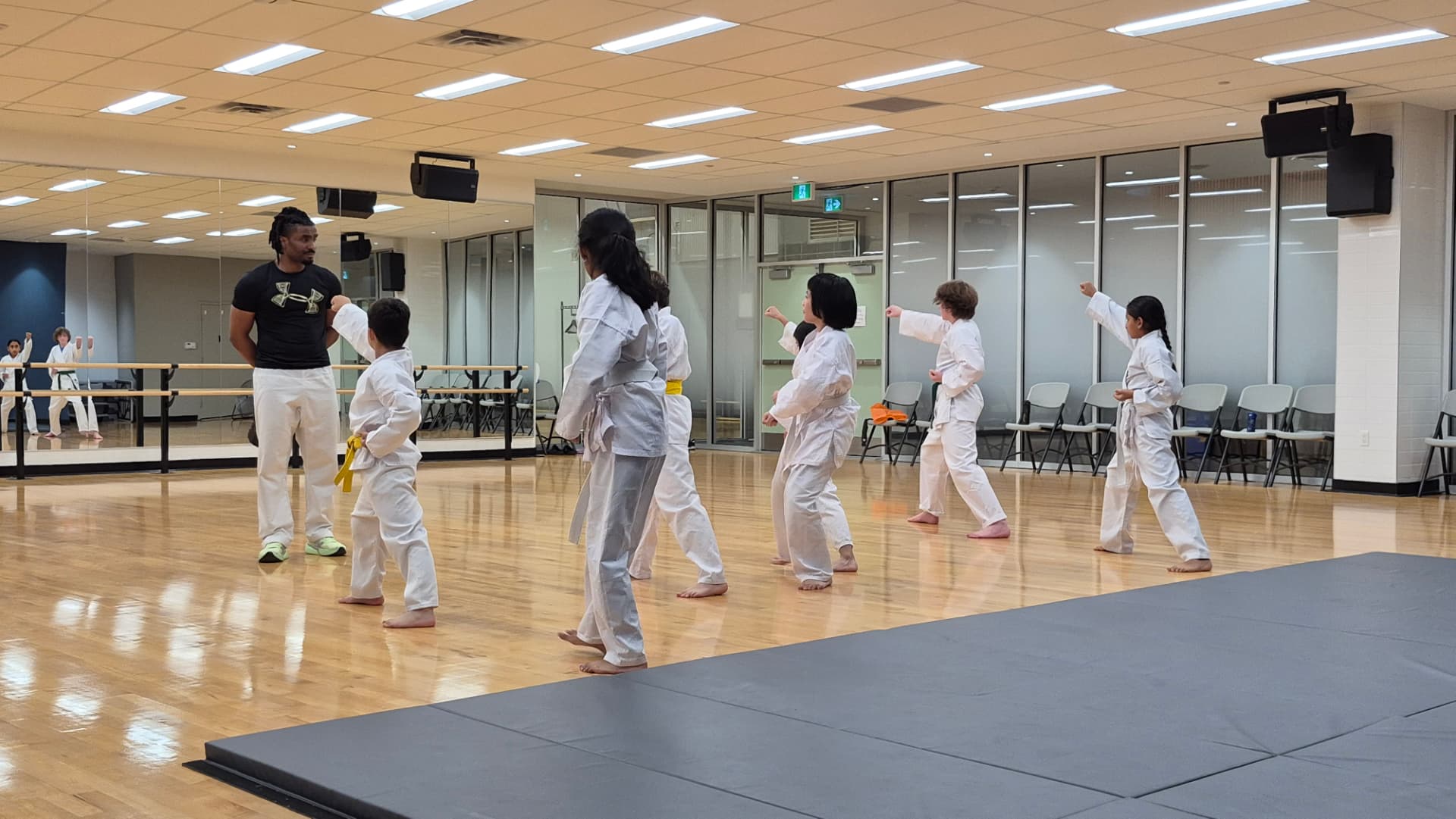 A karate class practises punches together under an instructor's guidance