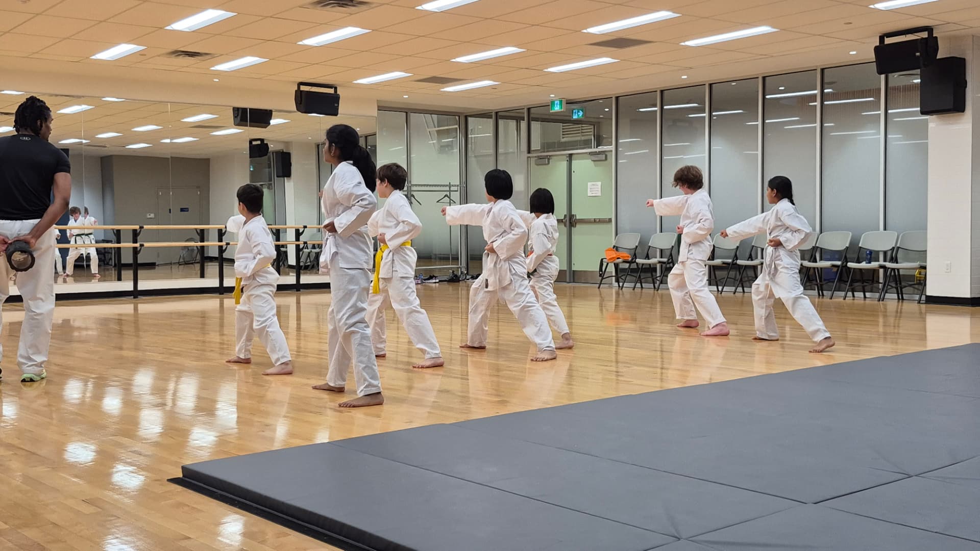 Children in white karate gi practising techniques together during a class with an instructor