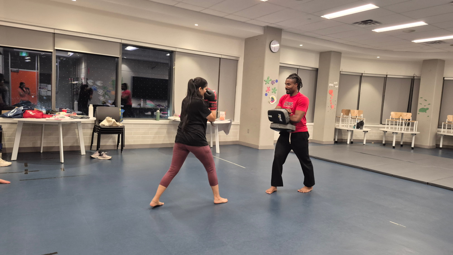 An adult student practises punches on pads held by an instructor in a kickboxing class