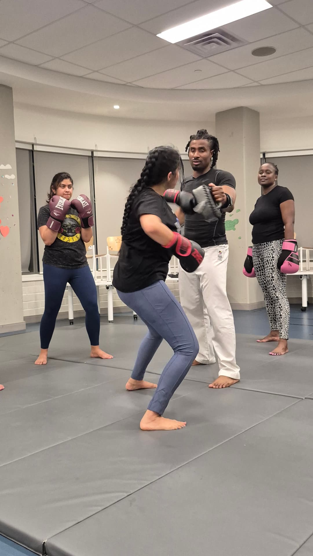 An adult student lands a controlled kick on focus mitts during a kickboxing session